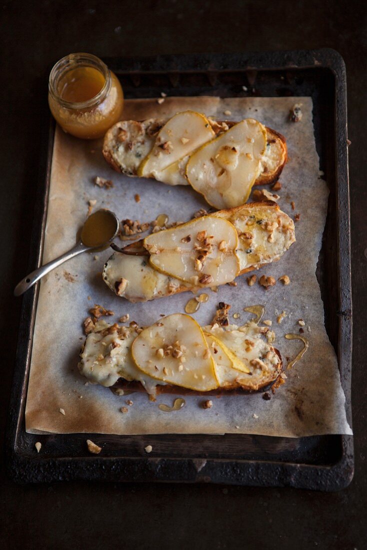 Slices of bread topped with pears, blue cheese and honey