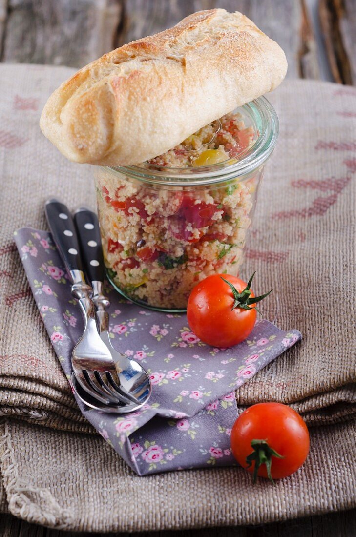 Couscous salad in a jar with a baguette and tomatoes