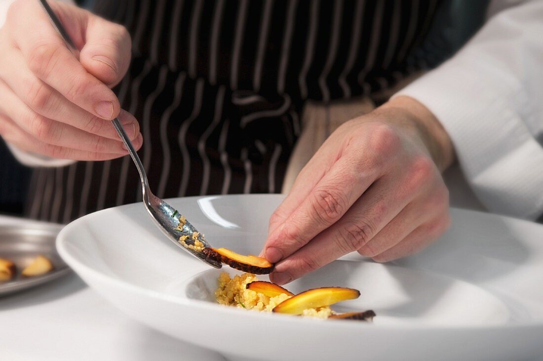 A chef putting a dish together on a plate