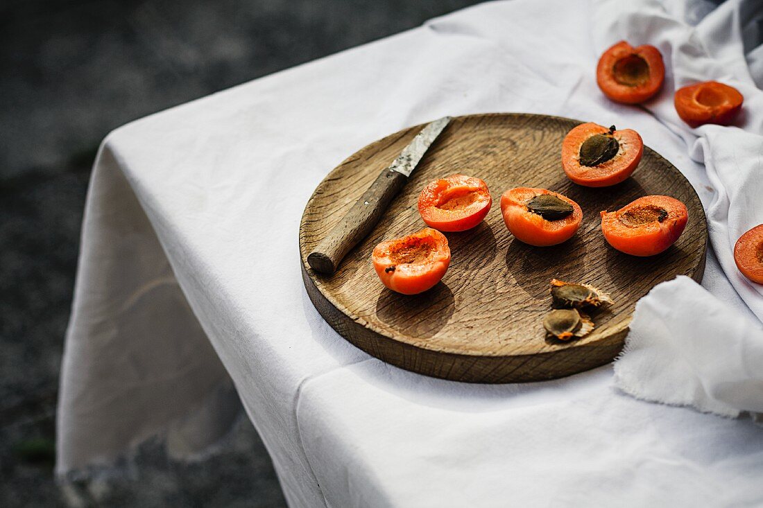 Halved apricots on a wooden plate