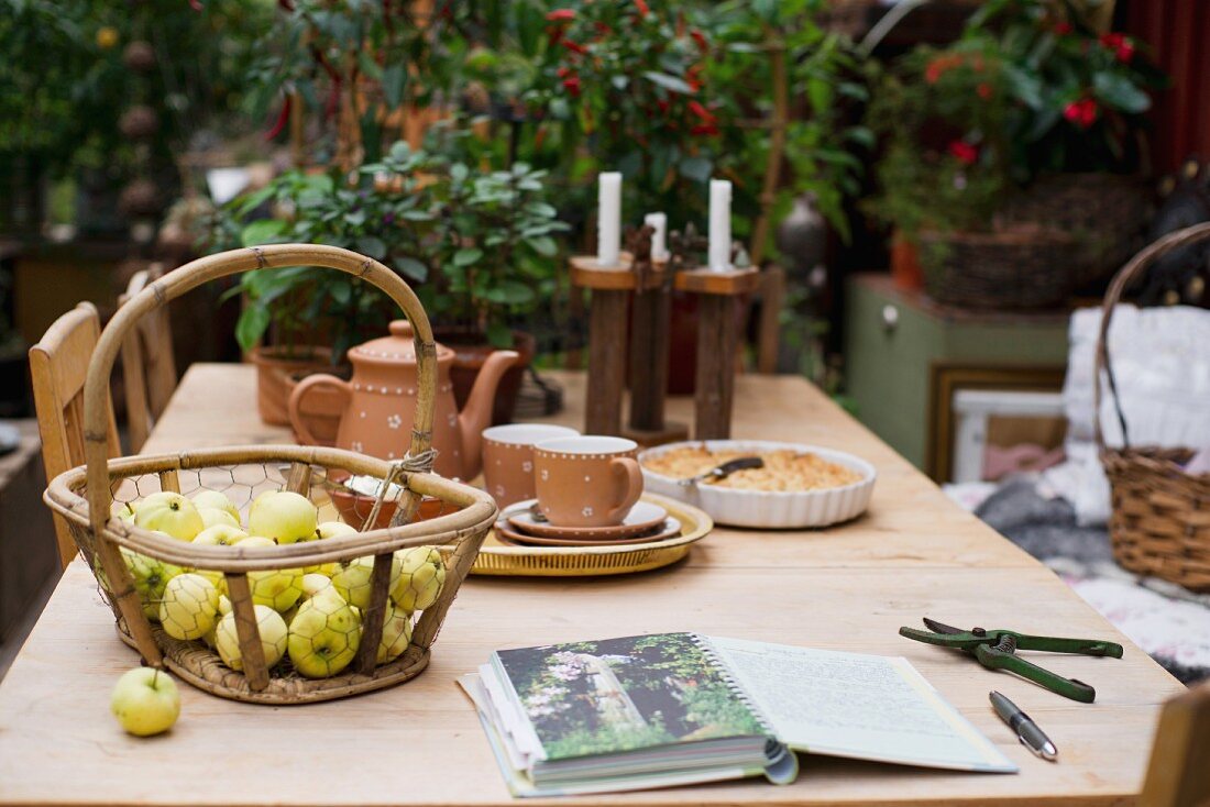 Korb mit Äpfeln und ländliches Kaffee Service auf Holztisch