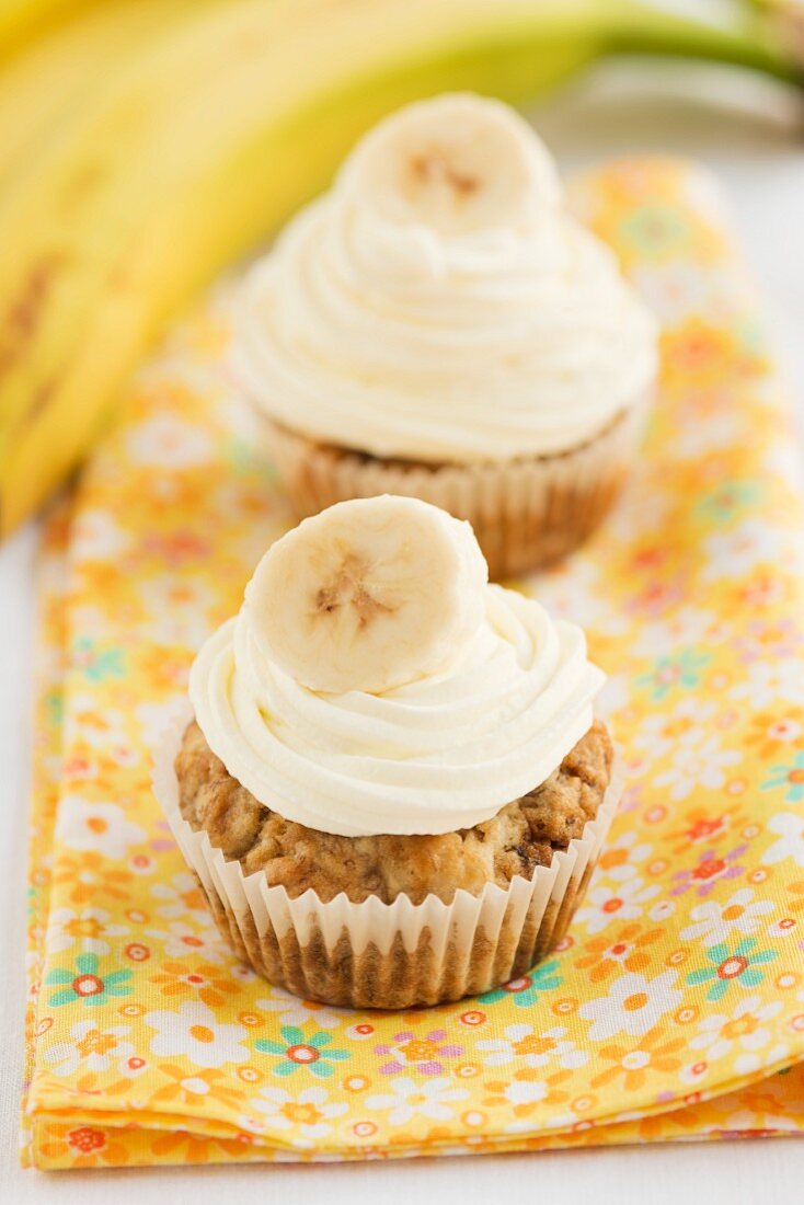 Two banana cupcakes on a floral cloth