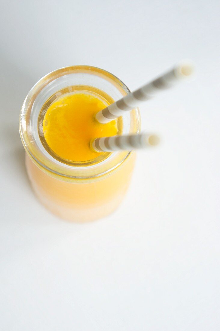 A bottle of orange juice with straws