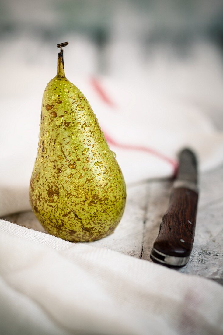 A freshly washed pear on a white wooden board