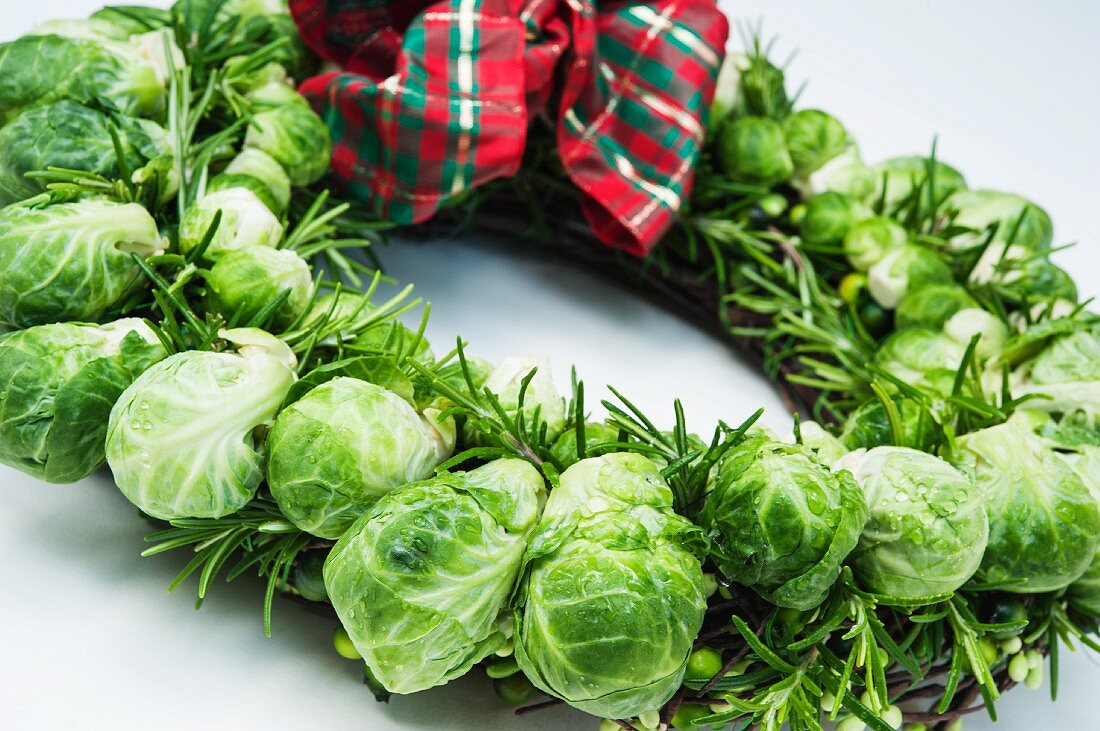 A Christmas wreath made with Brussels sprouts and rosemary with a checked ribbon