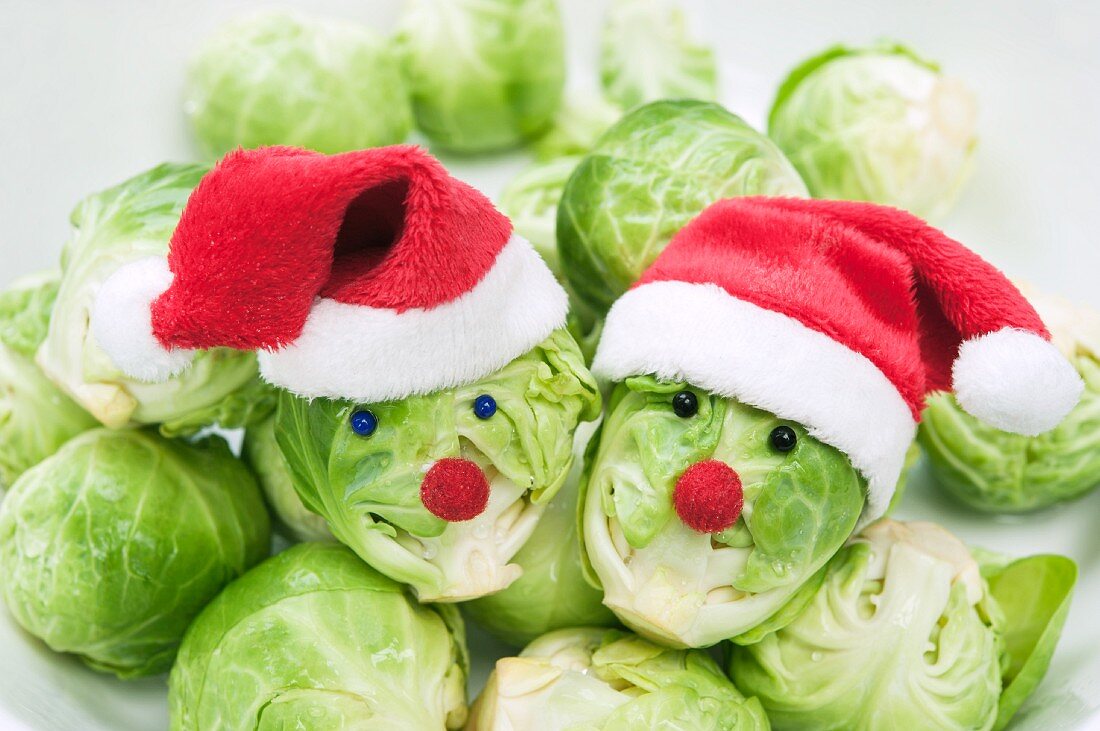 Two Brussels sprouts with faces wearing Christmas hats