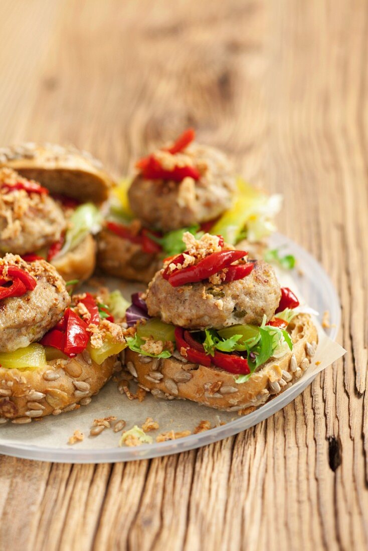 Burgers topped with marinated peppers and gherkins