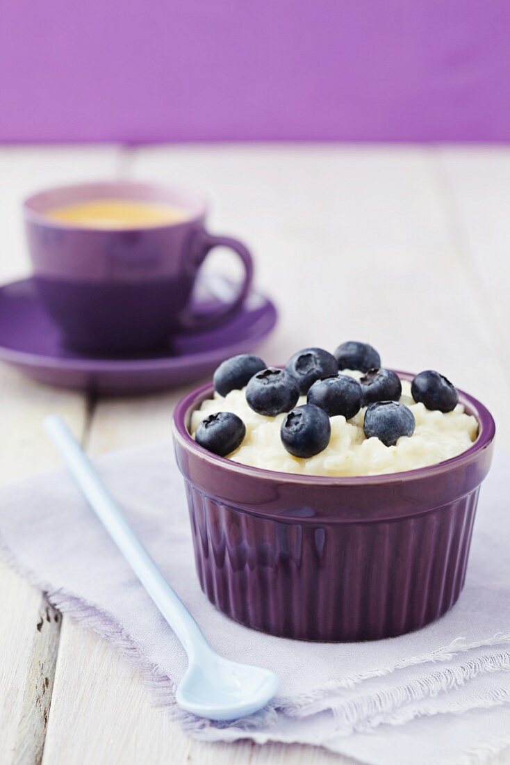 Rice pudding with blueberries and a cup of coffee in background