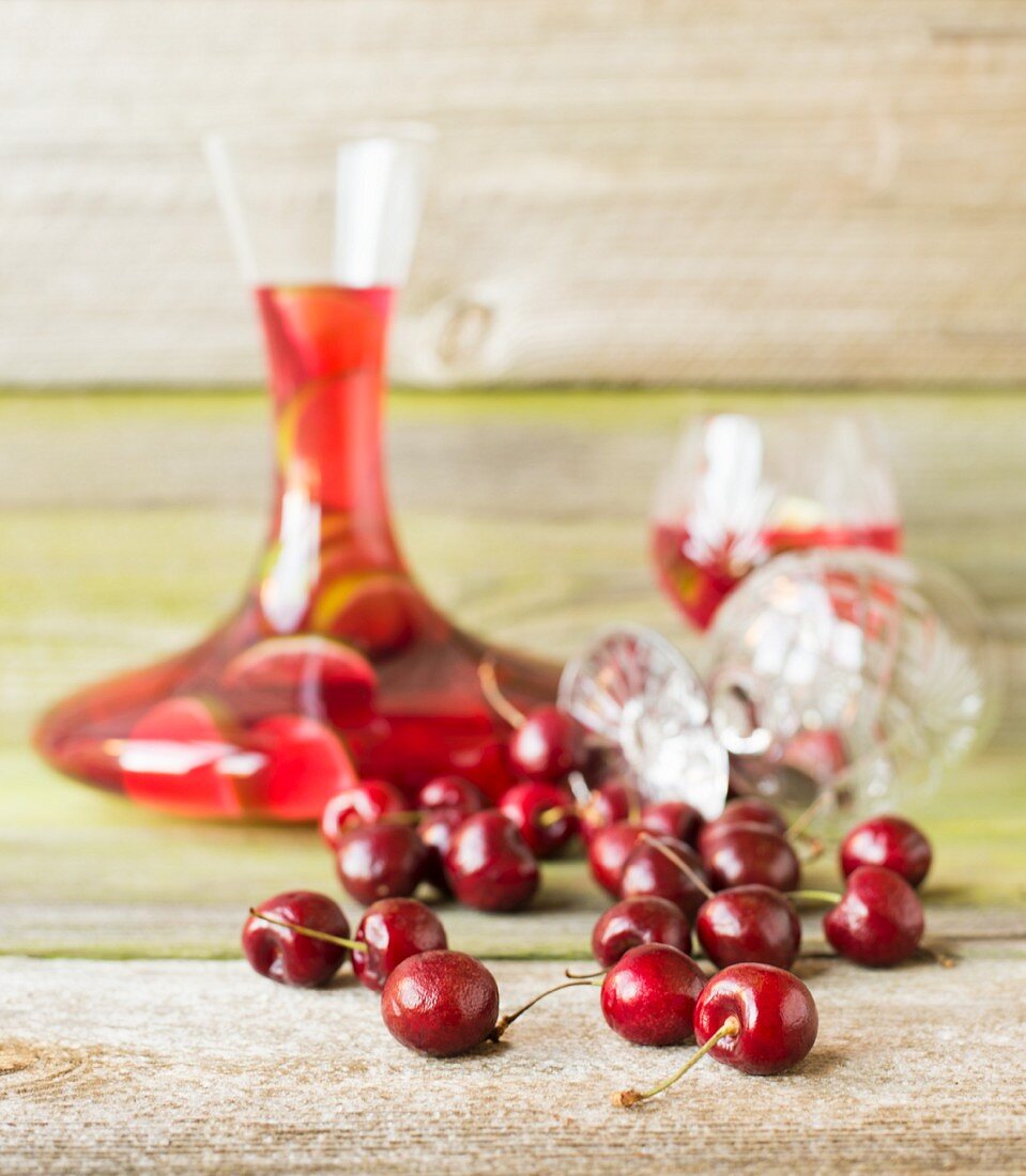 Fresh cherries in front of a carafe of cherry and lime cocktail