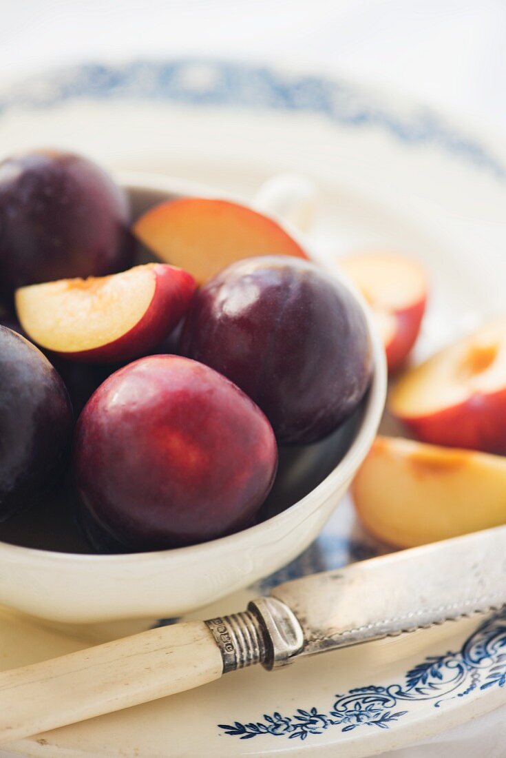 A bowl of plums with a vintage knife