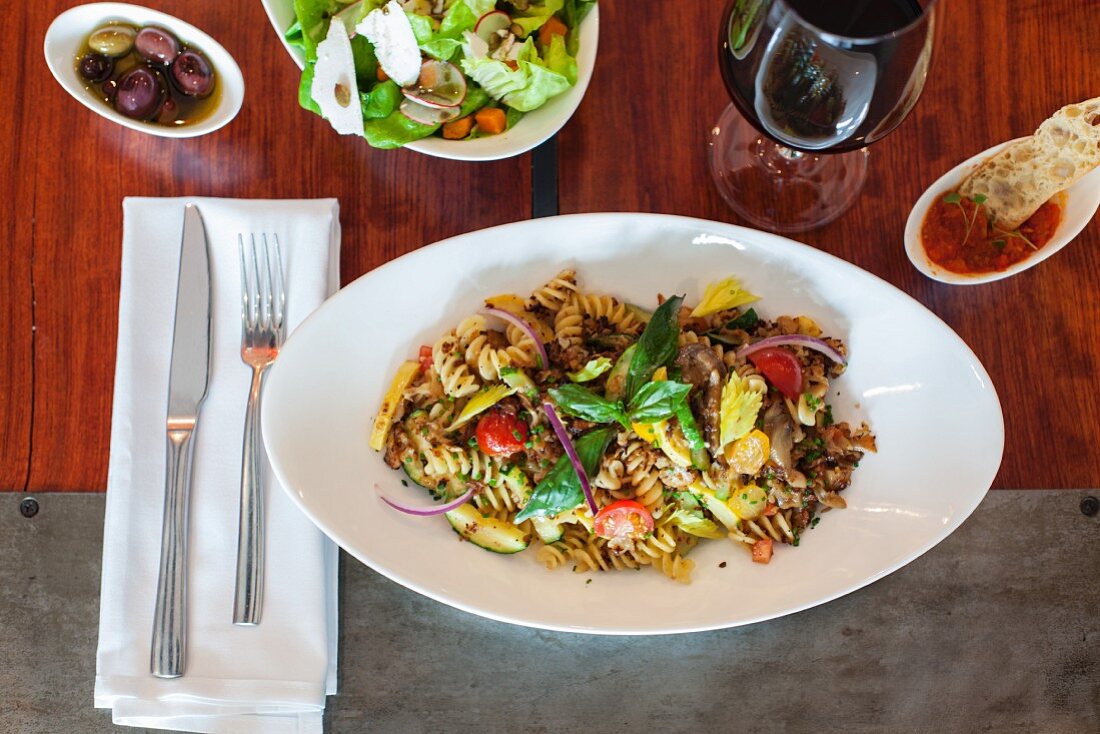 Fusilli with vegetables, salad and red wine