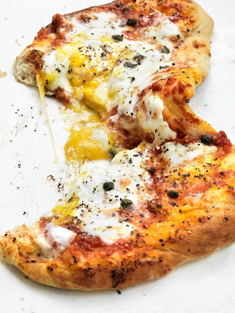 A pizza topped with egg and capers