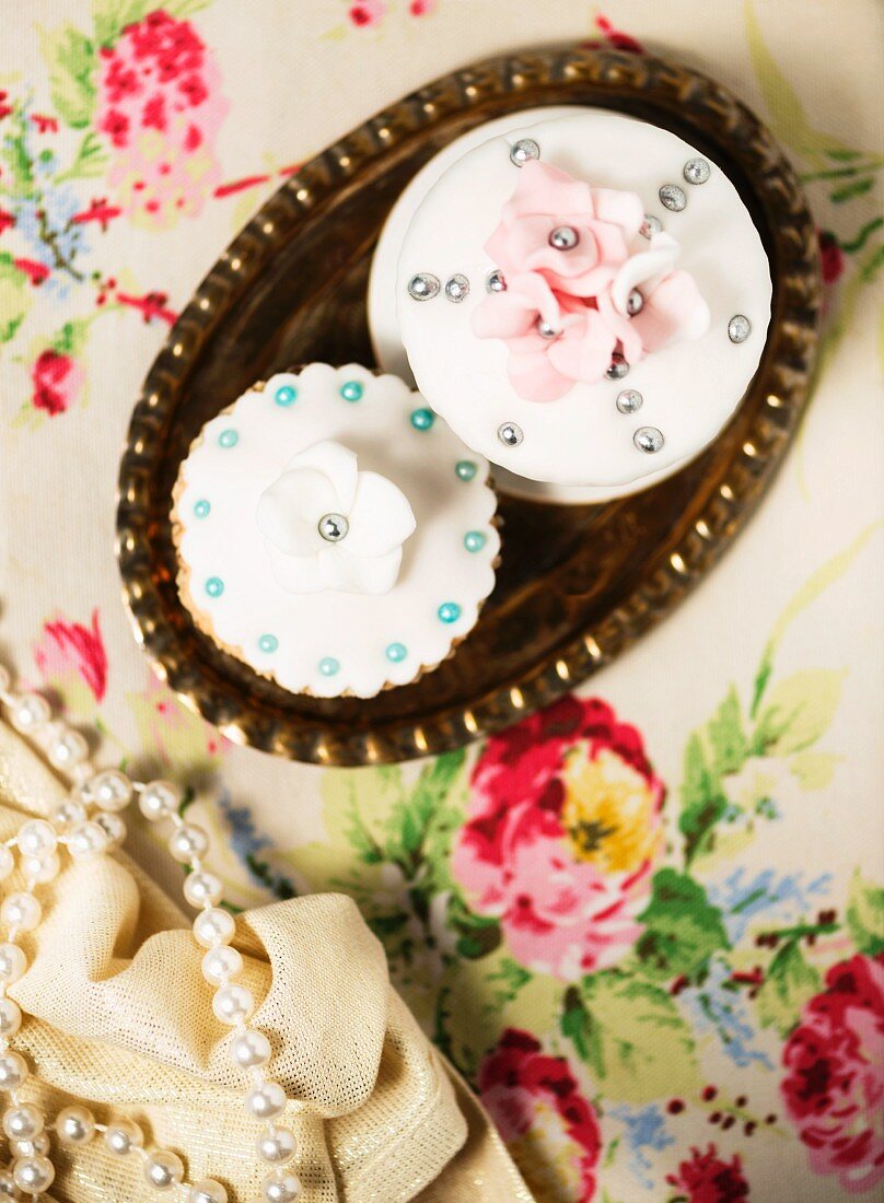 Festliche Cupcakes mit Zuckerperlen und Zuckerblumen