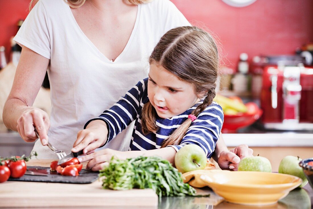 A mother and daughter chopping vegetables