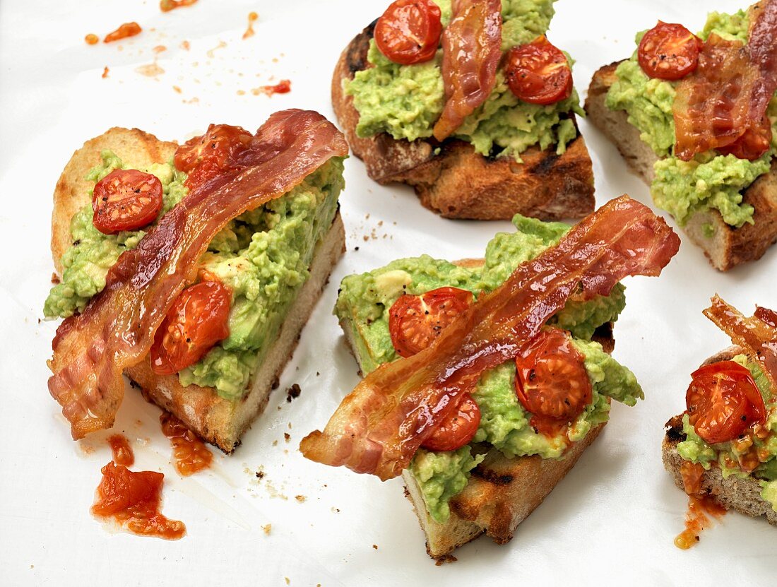 Toast topped with bacon, guacamole and tomatoes