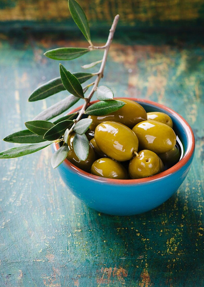 A bowl of marinated olives with an olive sprig
