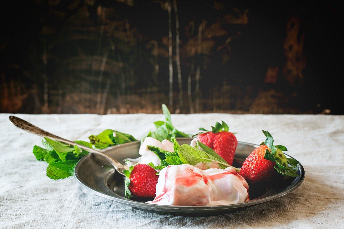 Strawberry ice cream with fresh mint and strawberries on a vintage plate