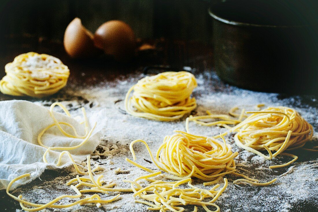 Homemade pasta on a wooden table with flour