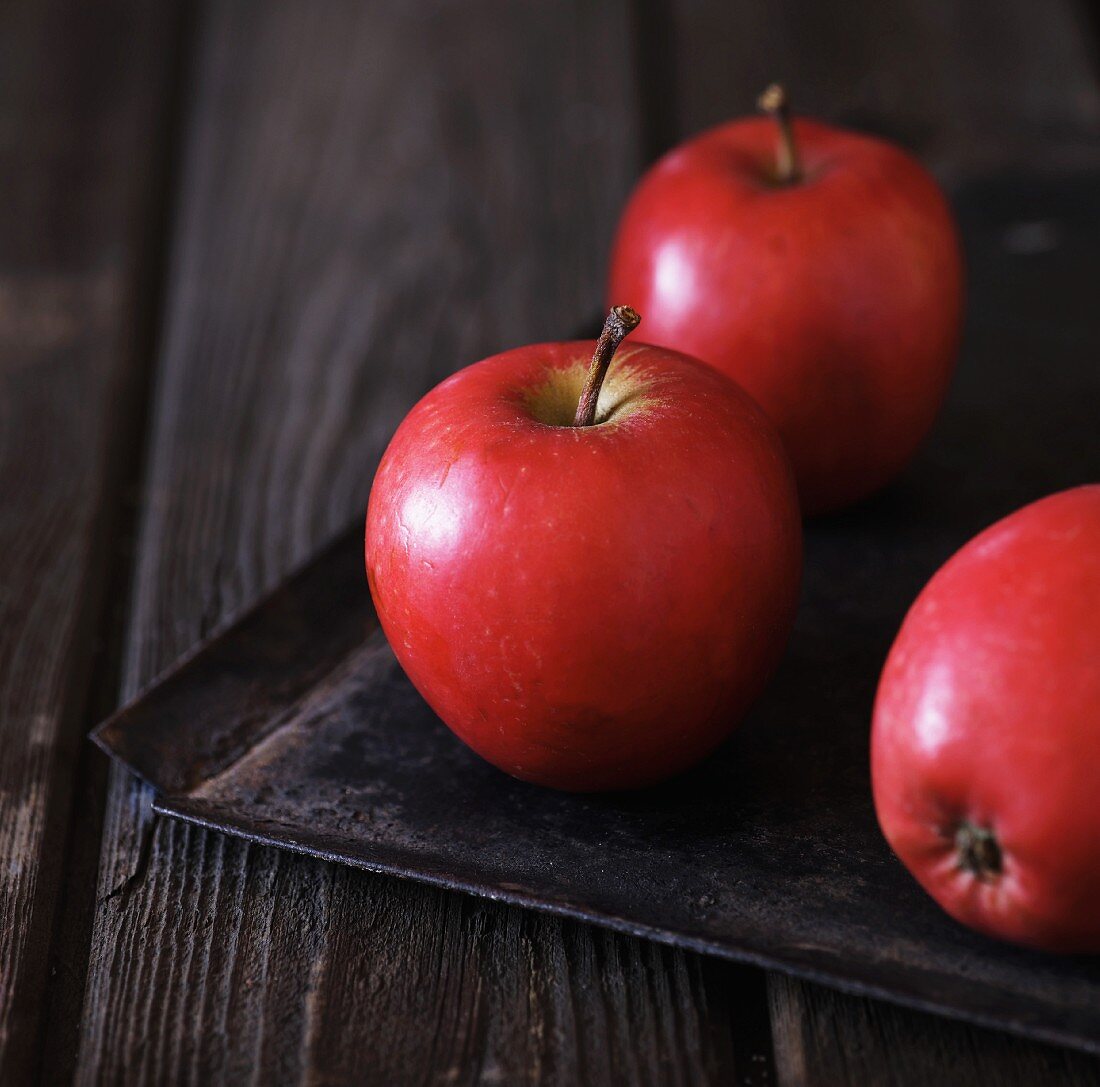 Rote Äpfel auf schwarzem Backblech
