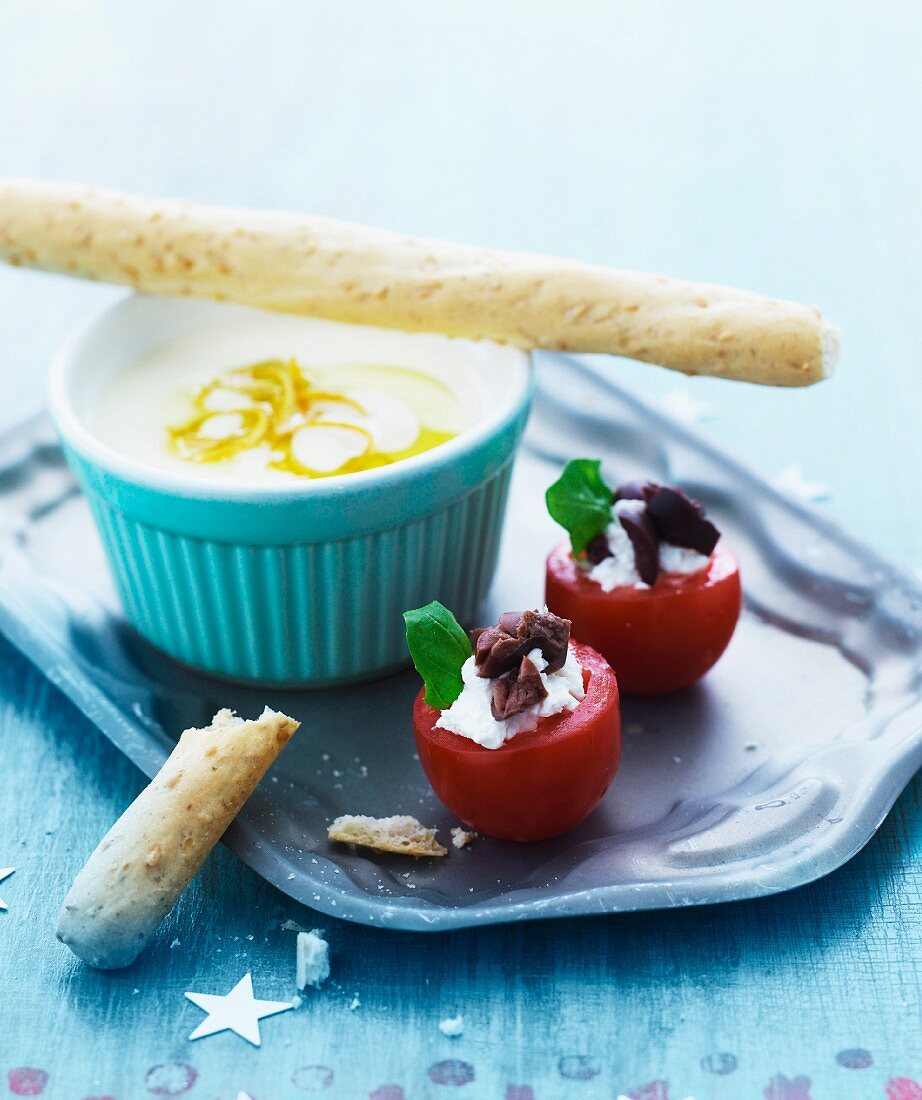 Mit Frischkäse und Oliven gefüllte Tomaten und Zitronencreme mit Grissini