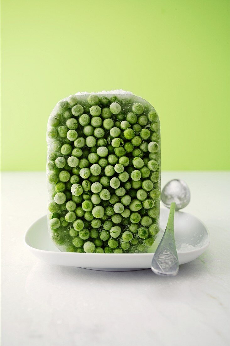 A block of frozen peas with a spoon