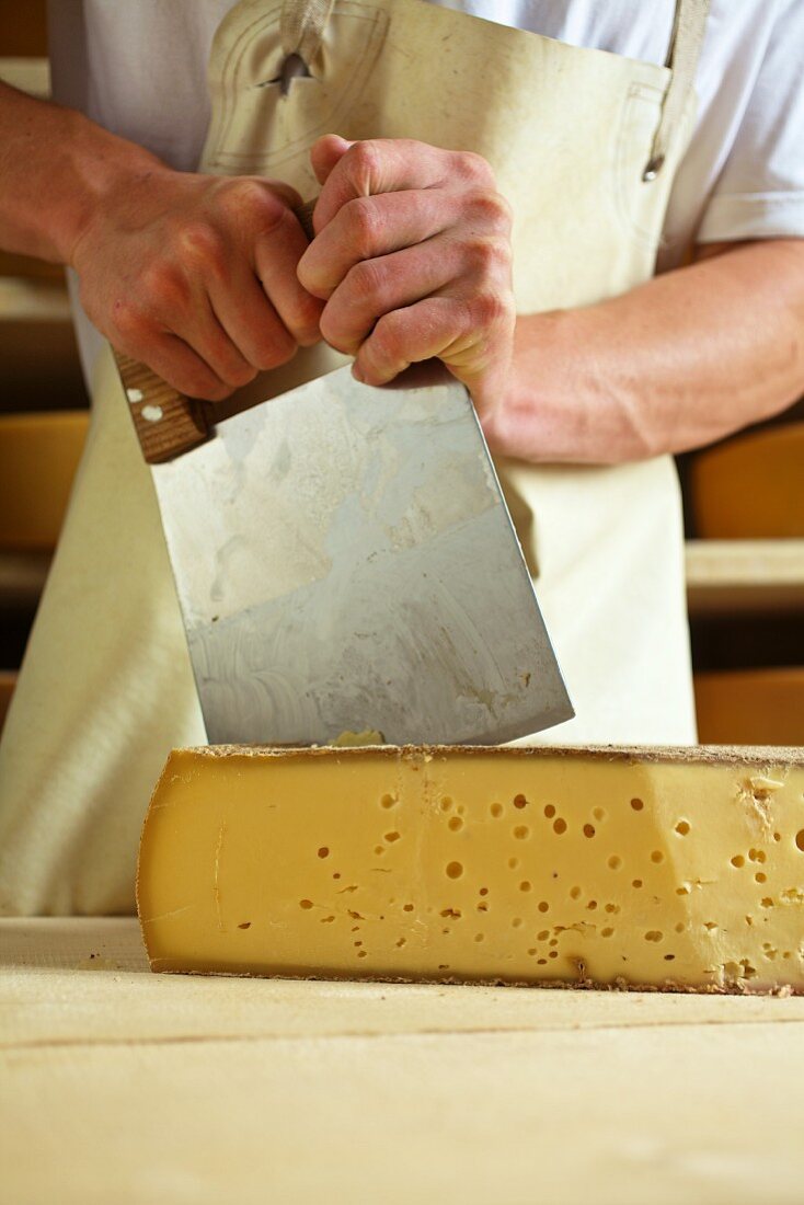 A dairyman cutting mountain cheese (Bregenzerwald, Vorarlberg, Austria)