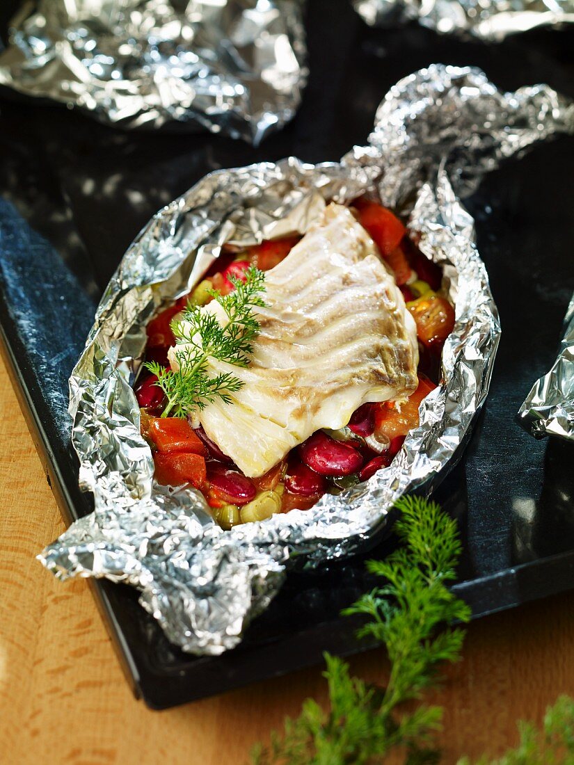 Pollack fillet on a bed of vegetables in aluminium foil