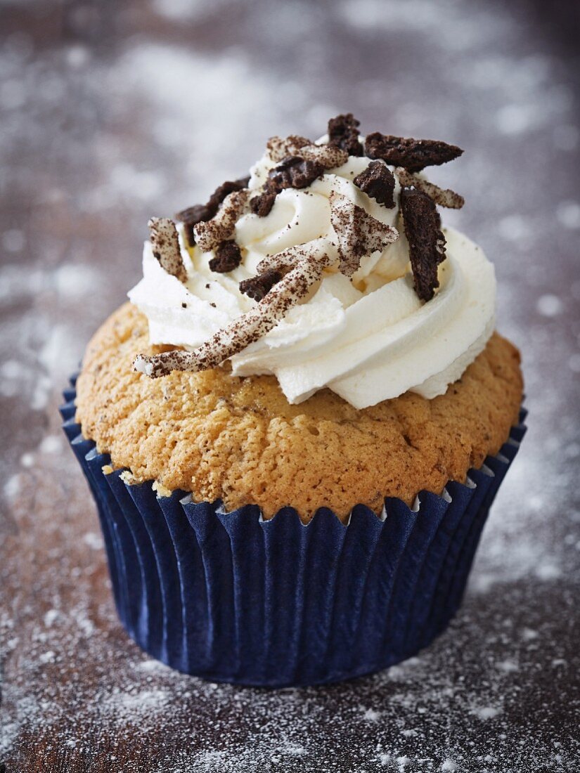 A cupcake topped with buttercream and chocolate biscuits