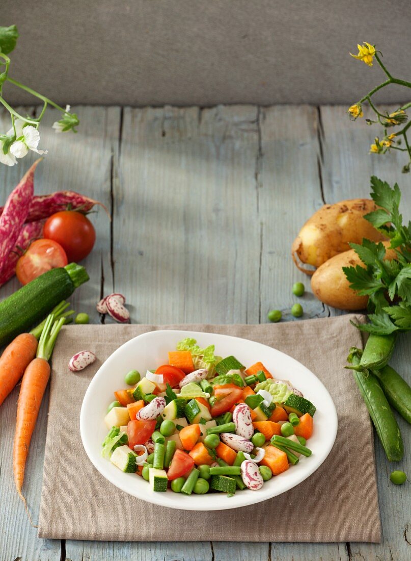 Zutaten für Gemüsesuppe auf Teller und daneben