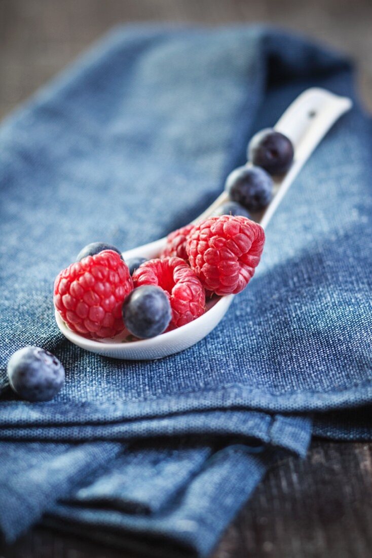Raspberries and blueberries on a porcelain spoon