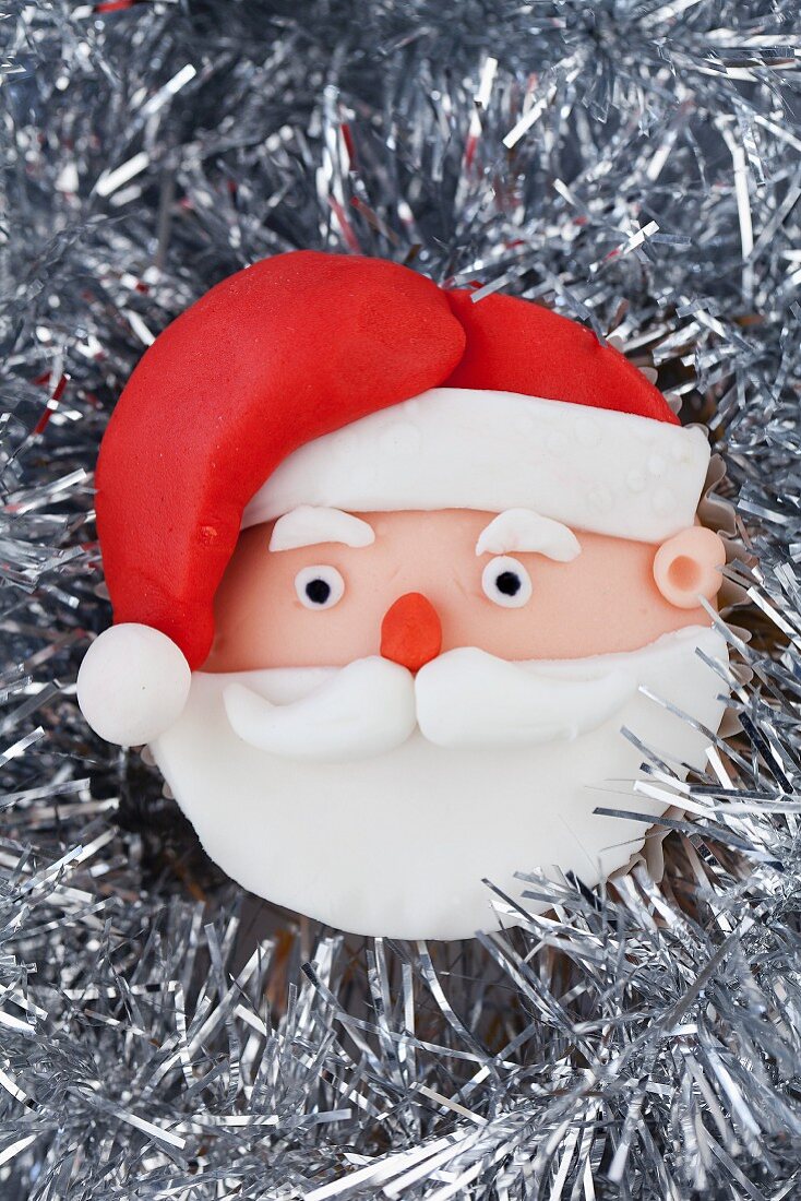 A Father Christmas cupcake on silver tinsel
