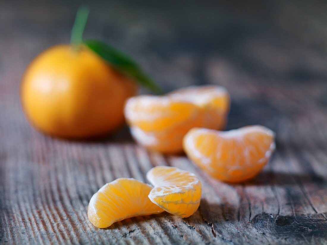 Mandarin segments with a whole mandarin in the background