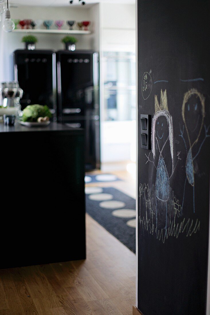 View into kitchen with child's drawing on blackboard wall to one side