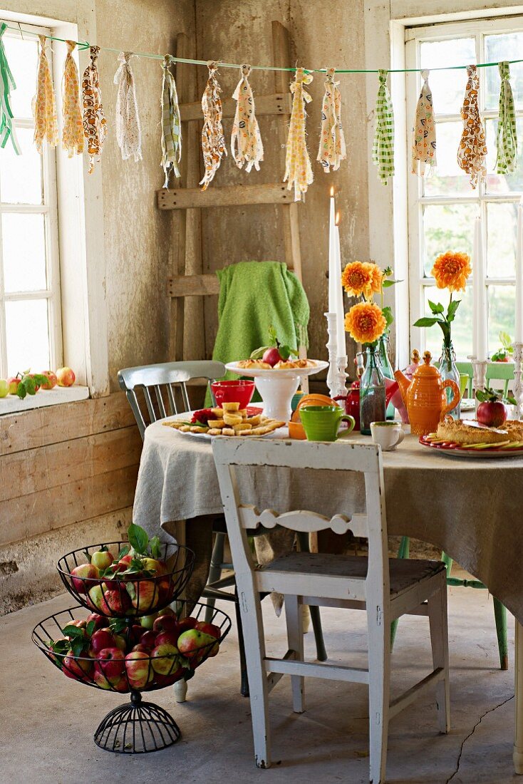 Gedeckter Tisch mit Apfelchips, Apfelgebäck, Blumenvasen und Teegeschirr