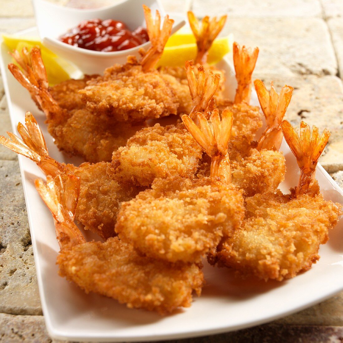 Breaded fried prawns with lemon slices and a seafood sauce