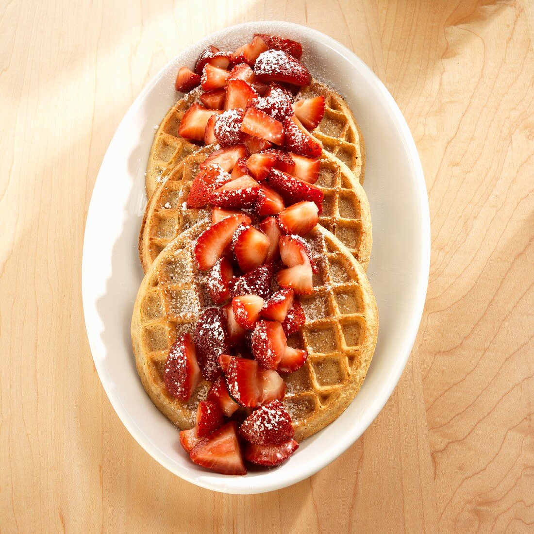 Wholemeal waffles with strawberries and icing sugar