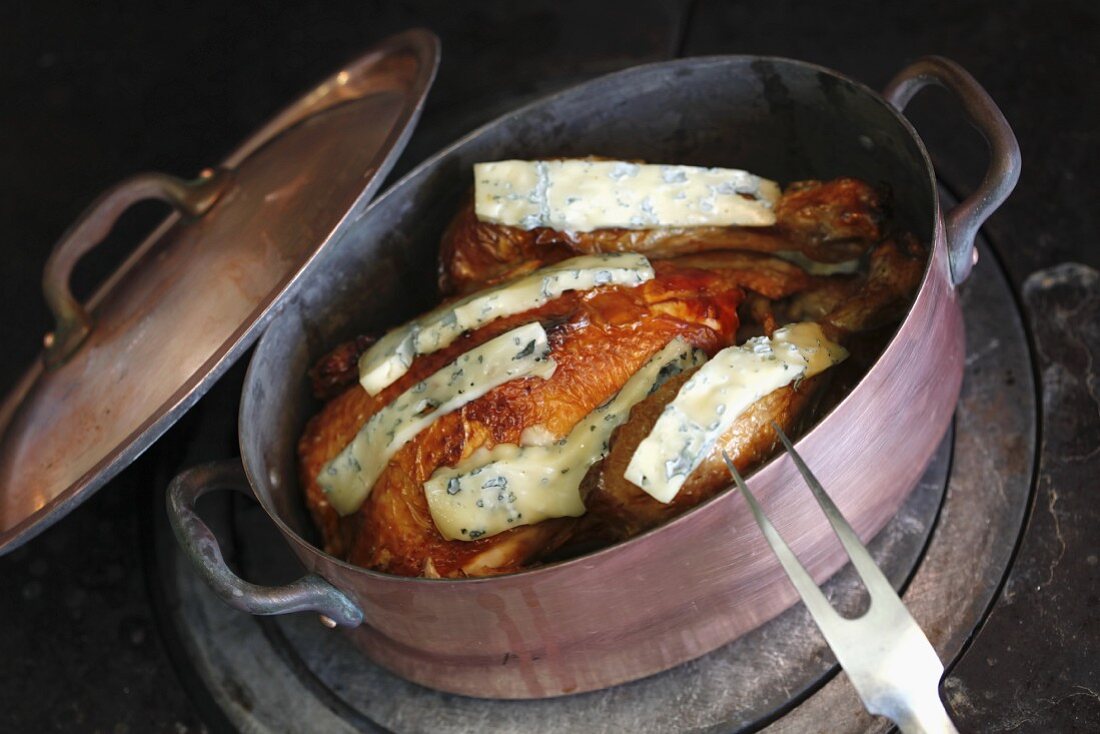 Chicken with blue cheese in a copper pot on a hob