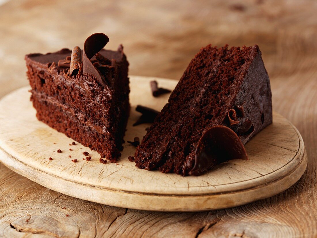 Two slices of chocolate cake on a wooden plate