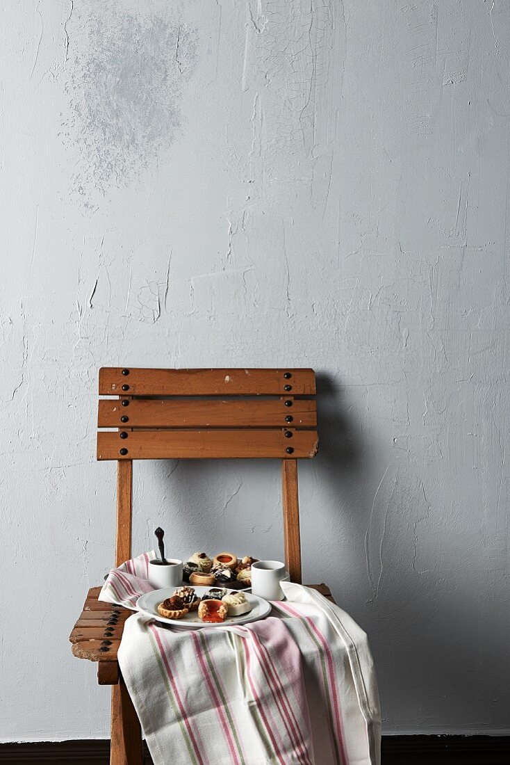 Coffee, tartlets and biscuits on a wooden chair