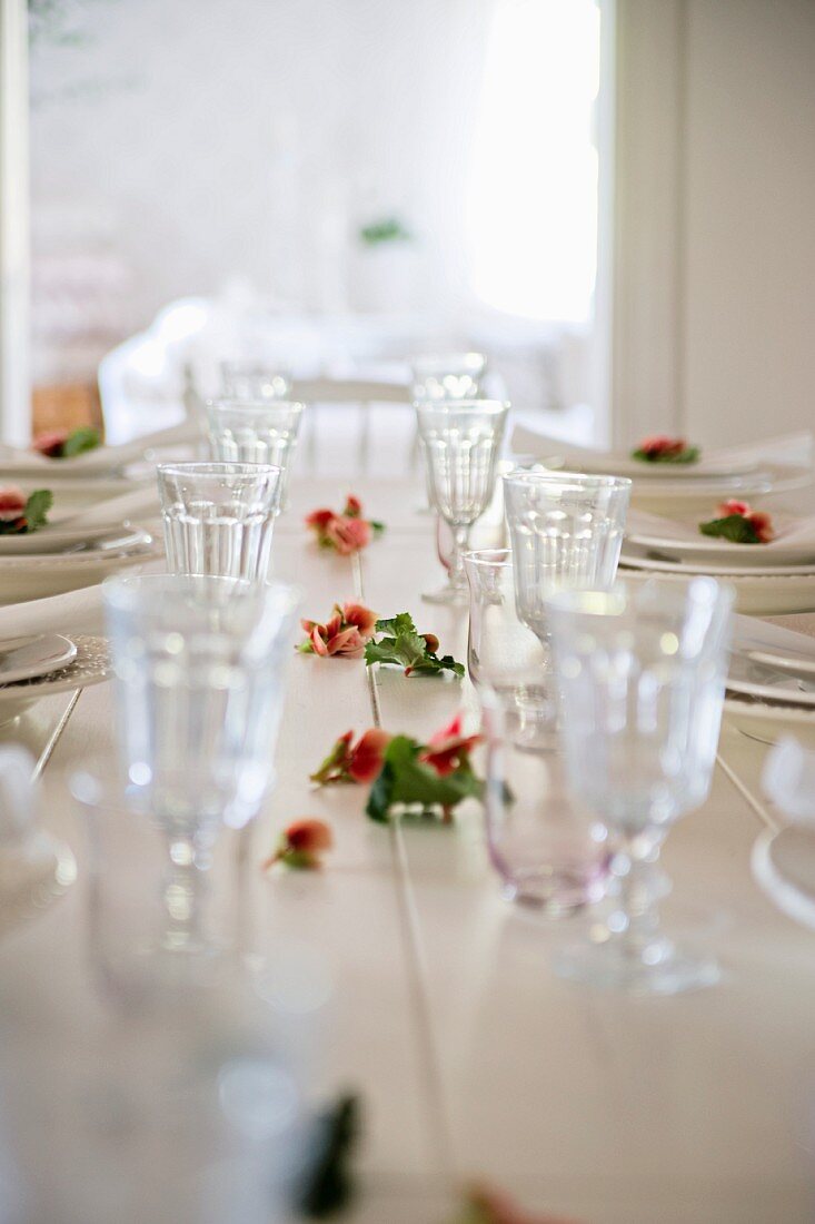 Set, white dining table with roses strewn amongst glasses