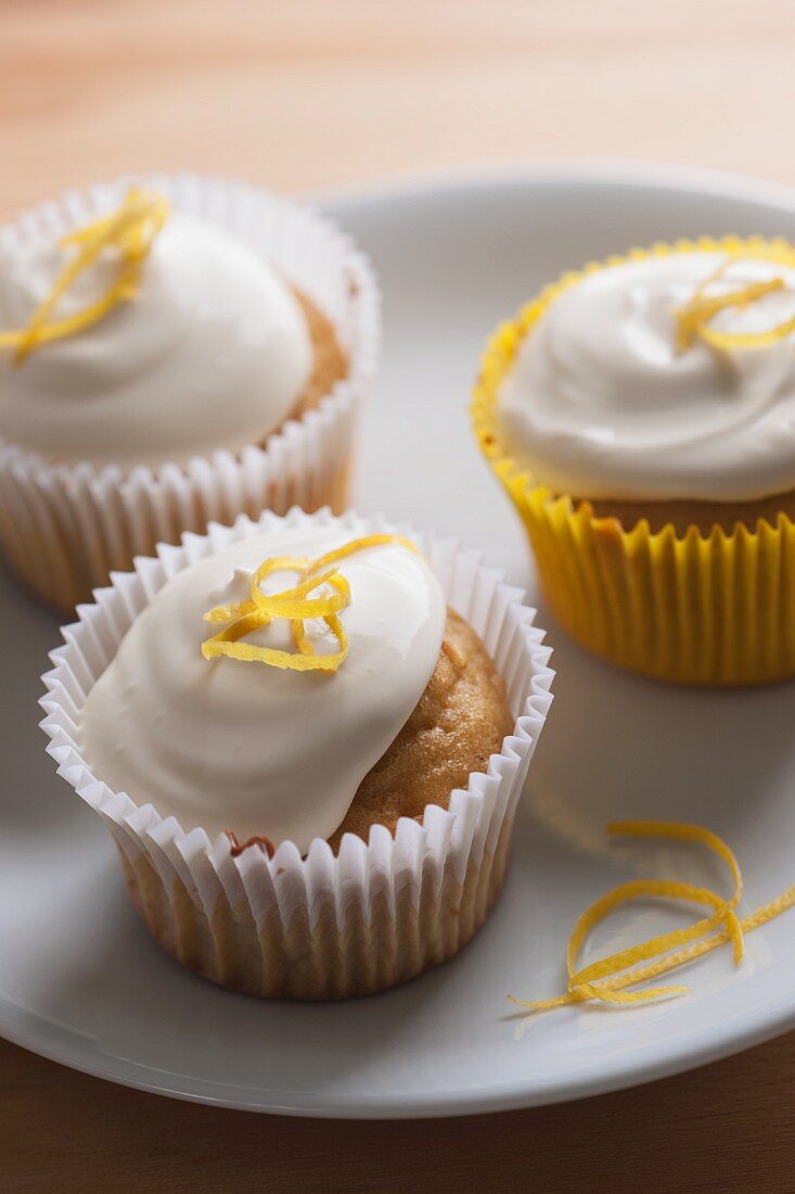 Drei Zitronen-Cupcakes mit Sahne und Zitronenzesten