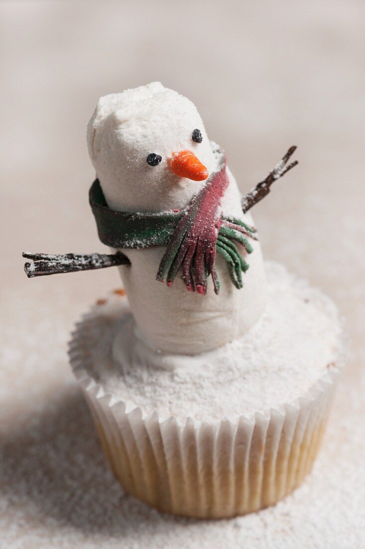 A snowman cupcake with icing sugar for Christmas