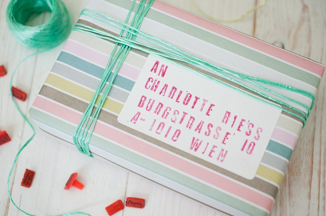 Hand-crafted label with stamped address on gift wrapped in striped pastel paper with matching ribbon