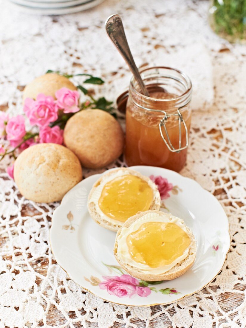 A jar of apple jelly and fresh bread rolls