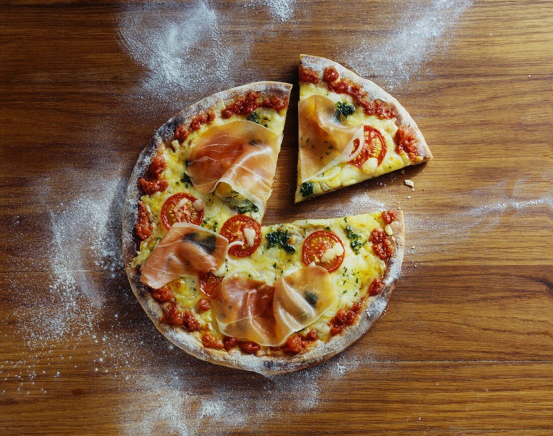 A Parma ham, cheese and tomato pizza, sliced