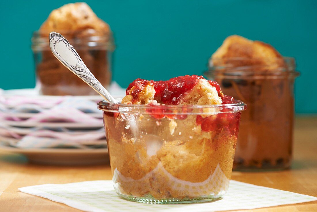 A peanut muffin with raspberry jam in a jar with a bite taken out