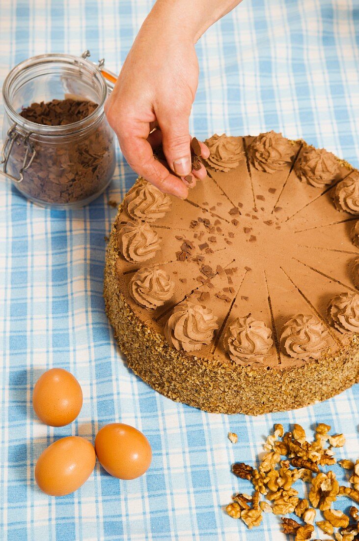 Nougat cake being decorated with chocolate sprinkles