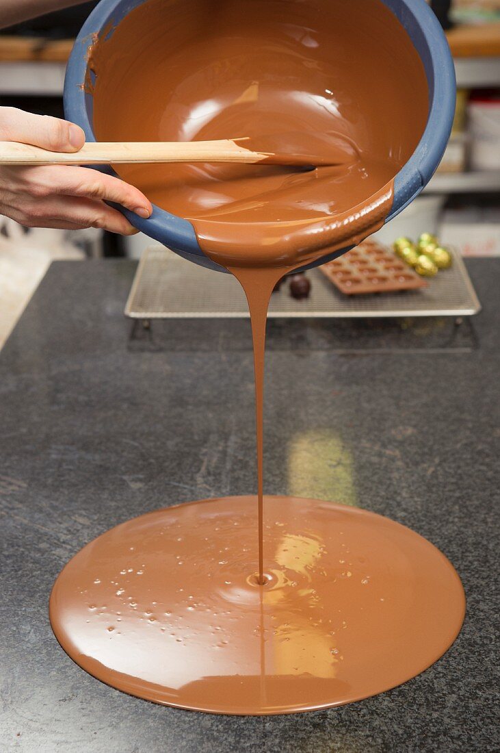 Melted chocolate being poured onto a marble surface