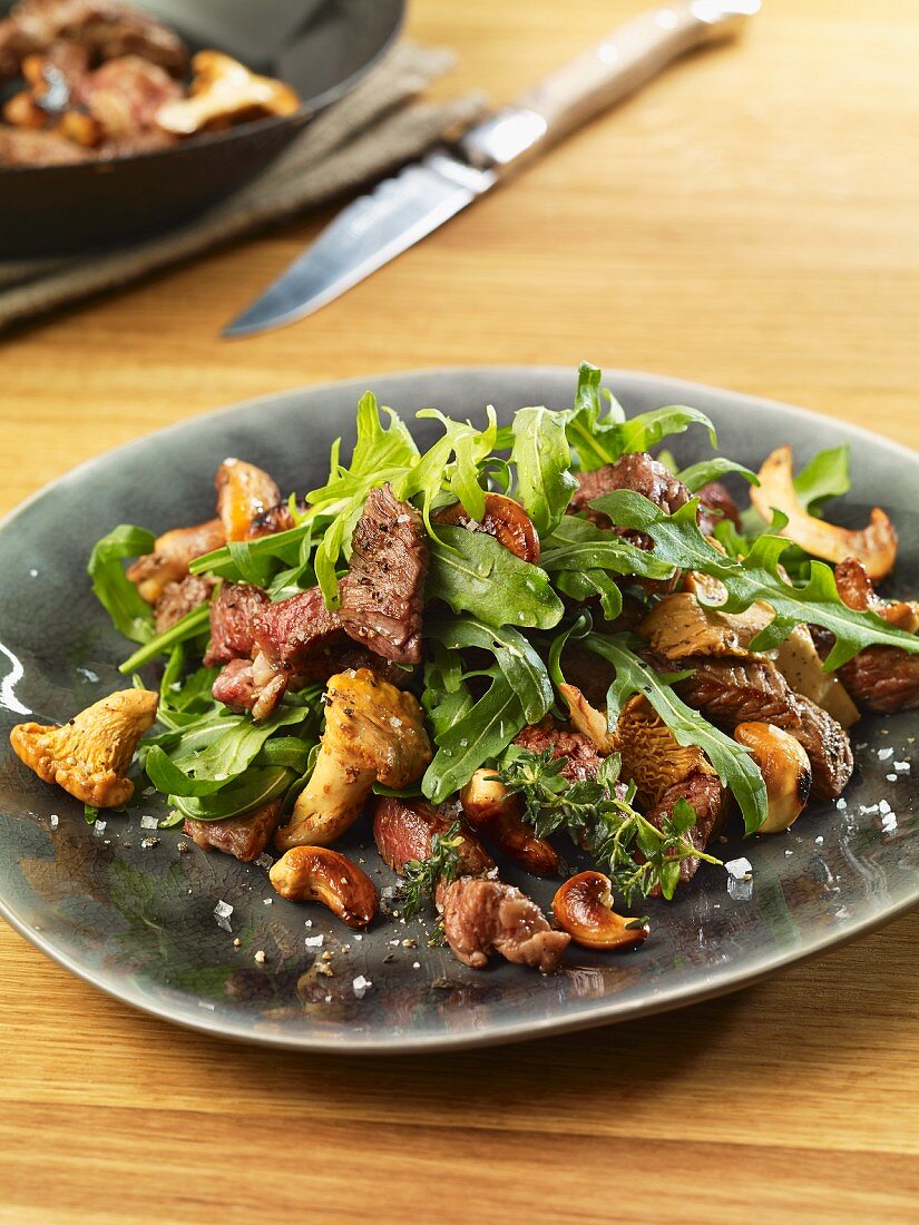 Rocket salad with beef strips, chanterelle mushrooms and pecan nuts