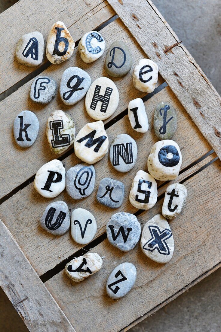 Collection of pebbles labelled with alphabet on wooden crate